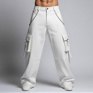 May include: White cargo pants with silver chain detailing and two front pockets with buckles. The pants have a wide leg design and are made of a smooth, solid white material. The pants are shown with white shoes.