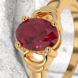 May include: A gold ring featuring a large, oval-cut ruby gemstone. The ruby is a deep red color and is set in a gold band with decorative accents. The ring is a close-up shot, highlighting the details of the gemstone and the setting.