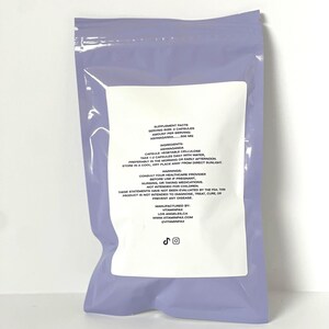 May include: A sealed, lavender-coloured plastic bag with a white label detailing supplement facts. The label lists ingredients, serving size, and warnings. The text includes "Ashwaganda" and "VitaminPax".
