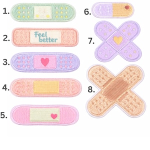 May include: Collection of eight embroidered patches in various designs. Includes bandages in pastel colors like pink, lavender, and peach, some with heart or text details. One patch reads "Feel better".