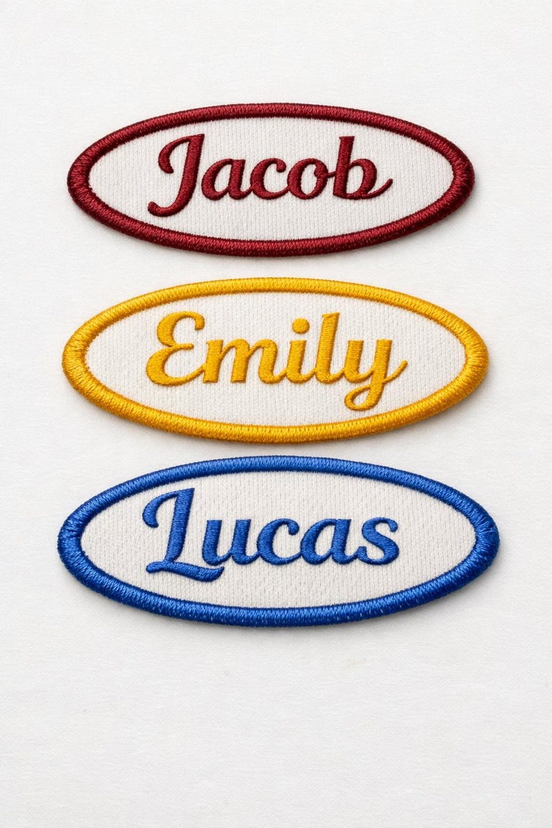 K&ouml;nnte beinhalten: Drei gestickte Namensaufn&auml;her: "Jacob" in Burgunderrot, "Emily" in Gold und "Lucas" in Blau. Jeder Name ist in Schreibschrift auf wei&szlig;em Hintergrund und von einem passenden ovalen Rand umgeben.