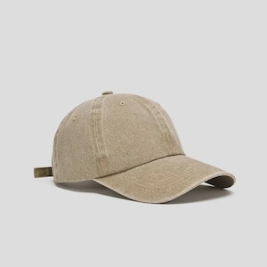 Op de afbeelding: Een beige baseballpet met een gebogen klep. De pet heeft een ontwerp met zes panelen, een knoop aan de bovenkant en een verstelbare band aan de achterkant. De stof lijkt op zacht, gewassen katoen.