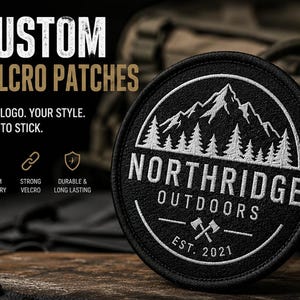 May include: A black, circular custom Velcro patch with white embroidered text and a mountain and tree design. The patch reads "NORTHRIDGE OUTDOORS EST. 2021". The text "CUSTOM VELCRO PATCHES" is above the patch.