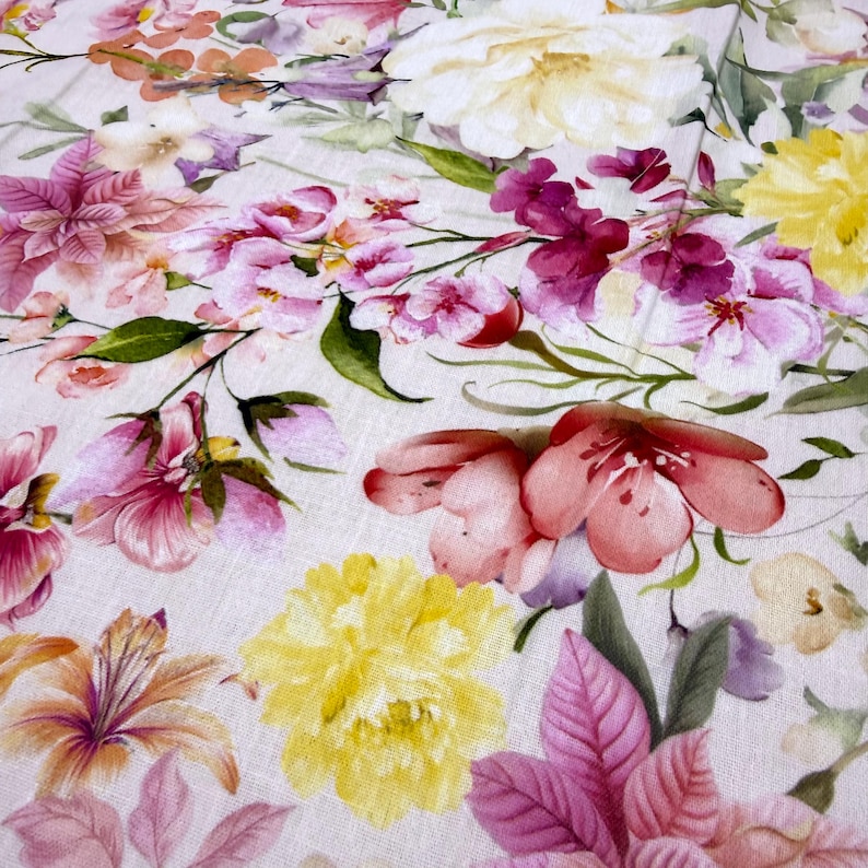 May include: A close-up of a floral pattern featuring a variety of flowers in shades of pink, yellow, and purple. The flowers are arranged on a light-colored background, creating a soft and delicate aesthetic. The design is reminiscent of a watercolor painting.