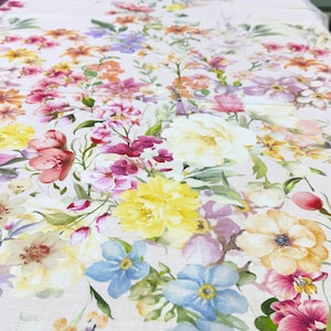 May include: A floral pattern tablecloth featuring a variety of colorful flowers in shades of pink, yellow, orange, purple, and blue. The flowers are arranged on a white background, creating a vibrant and cheerful design. The tablecloth is likely made of a soft fabric.