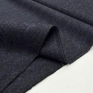May include: Close-up of a dark blue fabric with a subtle herringbone pattern. The fabric is folded, revealing the texture and weave. The edges are finished with a white stitch.