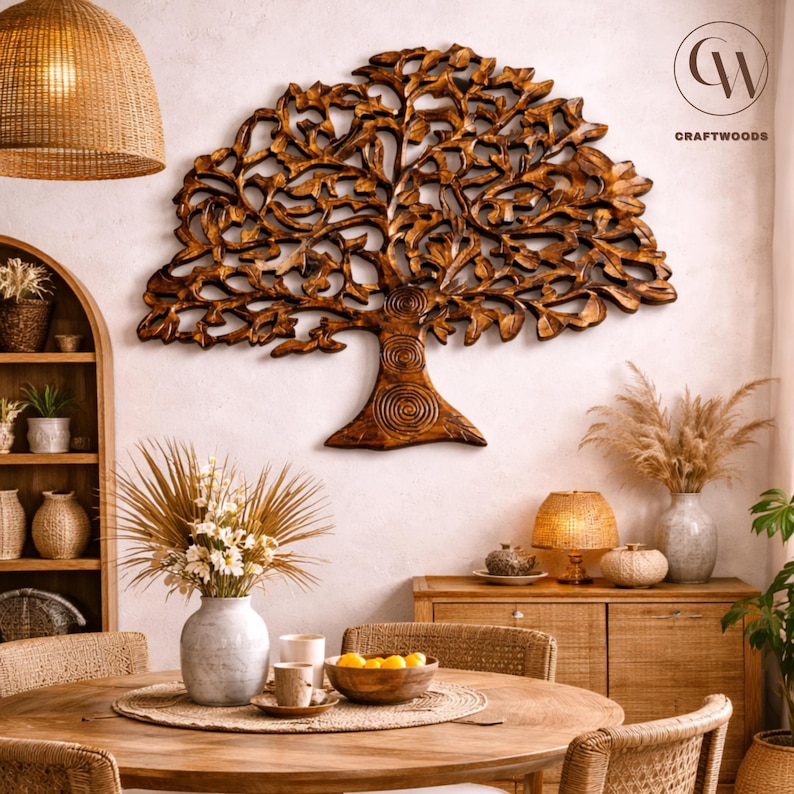 May include: A detailed wooden tree sculpture, mounted on a white wall. The tree features an intricate design of leaves and branches. The room is decorated with a round wooden table, vases, lamps, and other decorative items, creating a warm atmosphere.