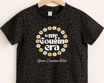 Kundenspezifisches Kleinkind-Gänseblümchen-Hemd, in meiner Cousin-Ära-Kleinkind-T-Shirt, weißes Gänseblümchen-Retro Blumen-Hemd, gefördert zum Cousin, Familien-passende Hemden