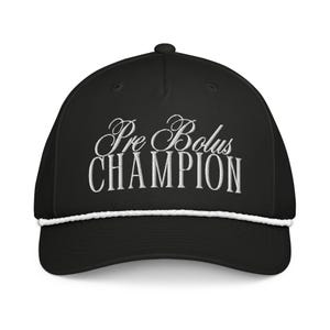 May include: Black baseball cap with white embroidered text that reads "Pre Bolus CHAMPION". The cap has a white rope detail along the brim.