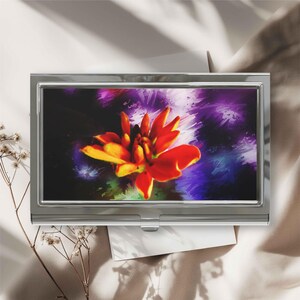 May include: A rectangular metal business card case featuring a glossy top surface with a vibrant, painterly illustration of a bright orange and yellow flower set against a deep, abstract purple and dark blue background with visible brushstrokes.