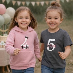 Peut inclure: Deux jeunes filles portant des vêtements sur le thème de l'anniversaire. L'une porte un sweat à capuche rose avec une couronne, le chiffre 4 et le nom "Amelie". L'autre porte un t-shirt gris avec le chiffre 5 et le nom "Lisa". Les deux sourient.
