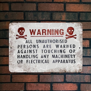 May include: A rectangular metal sign with a distressed white background and a red skull and crossbones graphic. The word "WARNING" is in red block letters above the text: "ALL UNAUTHORISED PERSONS ARE WARNED AGAINST TOUCHING OR HANDLING ANY MACHINERY OR ELECTRICAL APPARATUS."