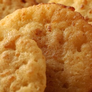 May include: Close-up of several golden-brown, round hash browns. The potato patties have a textured, slightly bumpy surface with visible crispy edges. The image highlights the appetizing texture and colour of the fried food.