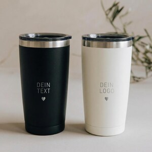 Könnte beinhalten: Zwei Edelstahl-Reisebecher, einer schwarz und einer weiß, mit silbernen Rändern und Deckeln. Der schwarze Becher hat den Text "DEIN TEXT" und ein Herzsymbol, der weiße "DEIN LOGO" und ein Herz.