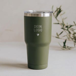 Könnte beinhalten: Olivgrüner isolierter Becher mit silbernem Rand und transparentem Deckel. Der Text "DEIN LOGO" ist auf der Vorderseite zusammen mit einem kleinen Herzsymbol aufgedruckt. Zum Warm- oder Kalthalten von Getränken.