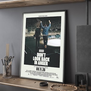 Puede incluir: Un póster de película enmarcado titulado Don't Look Back In Anger que muestra a dos figuras en un escenario de concierto frente a una gran multitud. El texto dice The Great Wait Is Over, Oasis, Don't Look Back In Anger, In Theaters And IMAX, 09.11.26.