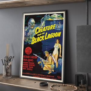 Può includere: Poster cinematografico vintage incorniciato per "Creature from the Black Lagoon". Il poster presenta una creatura verde, una donna in costume da bagno bianco e un uomo con un fucile subacqueo. Il testo include il titolo del film e i nomi del cast. Il poster è in una cornice nera.