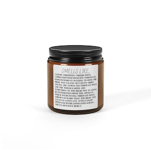 May include: A brown glass jar with a black lid, displaying a white label with the text "Smells Like" and a humorous description. The jar contains a scented product, possibly a candle or similar item.
