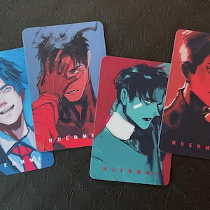 May include: Four rectangular art prints with portraits of young men in various poses. Each print uses a different colour palette, including blue, red, and teal. The artist's name, HUEDMMI, is printed at the bottom of each card.