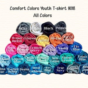 A colorful pyramid of rolled-up t-shirts in various colors, including gray, white, black, red, pink, blue, green, purple, orange, yellow, and more.