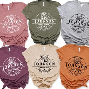May include: A collection of six short-sleeved t-shirts in various colors, including mauve, olive green, and orange. Each shirt features a circular graphic with the text "2025 JOHNSON FAMILY REUNION Chino, California."