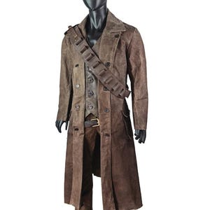 May include: A brown suede duster coat, vest, and pants set displayed on a mannequin. The coat is double-breasted with large buttons. A brown leather cartridge belt is worn over the vest. The outfit is a western-themed costume.