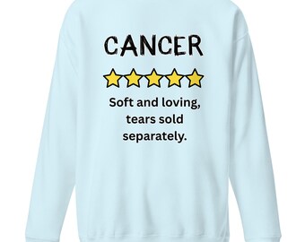 May include: Light blue sweatshirt with the word "CANCER" in black, above five yellow star outlines. Below the stars, the text reads "Soft and loving, tears sold separately."