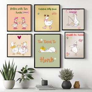 Könnte beinhalten: Eine Sammlung gerahmter Kunstdrucke mit skurrilen Gänse-Illustrationen. Jeder Druck, in einem schwarzen Rahmen, zeigt ein einzigartiges Design mit Text wie "Better with Two honks". Die Kunstwerke verwenden sanfte Farben und verspielte Bilder.