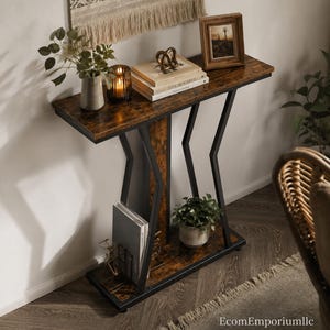 May include: A rectangular console table featuring a dark brown wood-grain finish top and bottom shelf supported by a black metal frame with angular, zig-zag side supports. The table includes a central vertical panel and a lower storage shelf.