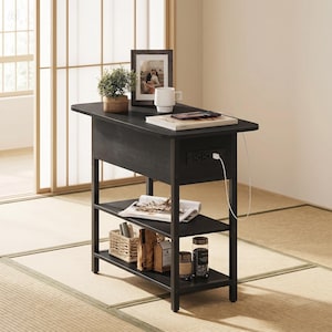 May include: A black side table with a built-in power outlet and three shelves. The top surface holds a framed photo, a mug, and a small plant. The table is 28 inches tall, 20 inches wide, and 12 inches deep.
