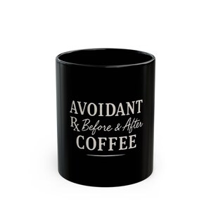 May include: Black ceramic coffee mug with white text that reads "Avoidant Rx Before & After Coffee". The mug is cylindrical and has a glossy finish. The text is centered on the mug.