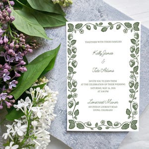 May include: Wedding invitation with a strawberry vine border. The invitation includes the names Kelly James and Tate Adams, and the wedding details: Saturday, May 16, 2006, at 3:00 PM, at Lionscrest Manor in Lyons, Colorado. Lilac and white flowers are in the background.