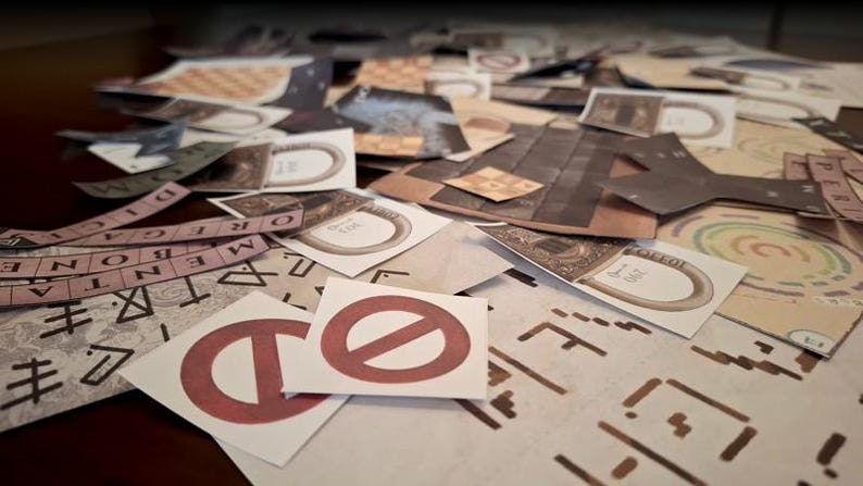 May include: A collection of game pieces, including cards with ring designs, strips of text, and cards with a red prohibition symbol. The pieces are scattered on a surface, suggesting a board game or puzzle.