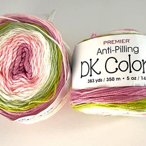 May include: Two skeins of Premier DK Colors yarn. The yarn is a gradient of pink, green, and white. The label reads "Anti-Pilling DK Colors" and lists the yardage as 383 yds and the weight as 5 oz (140 g).