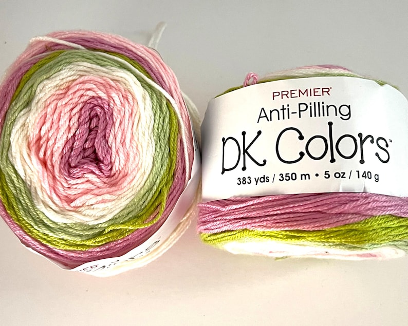 May include: Two skeins of Premier DK Colors yarn. The yarn is a gradient of pink, green, and white. The label reads "Anti-Pilling DK Colors" and lists the yardage as 383 yds and the weight as 5 oz (140 g).