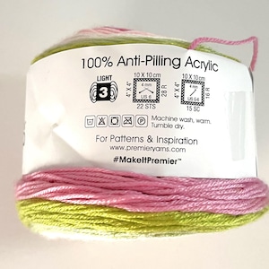 May include: A roll of multi-colored yarn with pink, green, and white strands. The label reads "100% Anti-Pilling Acrylic" and includes instructions for washing and care. The yarn is suitable for knitting and crochet projects.