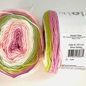 May include: Two skeins of Premier Yarns acrylic yarn in the Rose Garden colorway. The yarn is a blend of pink, white, and green. The label indicates the color number, manufacturer, and that it is made in Turkey.