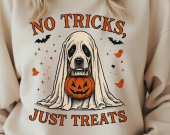 May include: Beige sweatshirt with a Halloween-themed graphic. The design features a dog dressed as a ghost holding a jack-o'-lantern. The text reads "NO TRICKS, JUST TREATS" in orange. Bats and orange ghosts are also included in the design.
