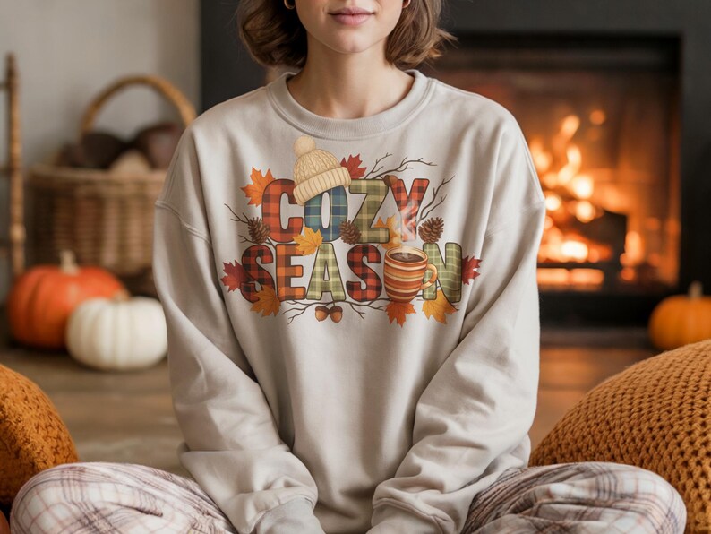 Cozy Season Png with plaid letters and rustic fall details including leaves, pinecones, acorns, and a steaming mug. Features groovy fall retro style with cozy sweater weather accents. Isolated on a white background, perfect for autumn sublimation projects, fall shirts, mugs, crafts, and diy seasonal decorations.