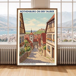 May include: A framed print of Rothenburg ob der Tauber, Germany, in a vintage travel poster style. The image shows a cobbled street with traditional buildings, a church tower, and the text "ROTHENBURG OB DER TAUBER". The bottom of the print includes the coordinates 49.38° N, 10.21° E.