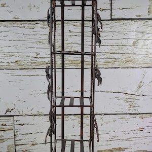 May include: A tall, wrought iron plant stand with four shelves and a woven top and bottom. The stand is dark brown with decorative leaf accents and is approximately 152 cm tall.