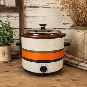 Peut inclure: Un autocuiseur de style vintage avec un extérieur crème moucheté, orné de bandes horizontales vertes et orange. Il est doté d'un couvercle en verre et d'un bouton de commande noir avec des réglages pour faible et élevé. Pour la cuisine.