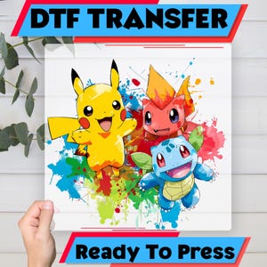 Könnte beinhalten: DTF-Transfer mit Pikachu, Glumanda und Schiggy mit bunten Farbspritzern. Der Text "DTF TRANSFER" steht oben und "Ready To Press" unten. Das Bild befindet sich auf weißem Hintergrund.