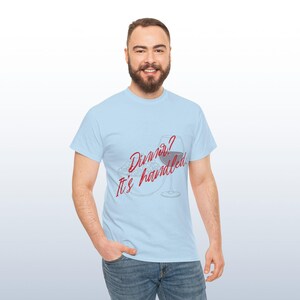 May include: Pale blue t-shirt featuring the red text "Dinner? It's handled." with a wine glass and plate graphic. The person is wearing blue jeans.