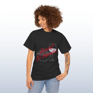 May include: Black t-shirt featuring a graphic of popcorn and a wine glass. The text on the shirt reads "Do what feels right". The design is in red and white.