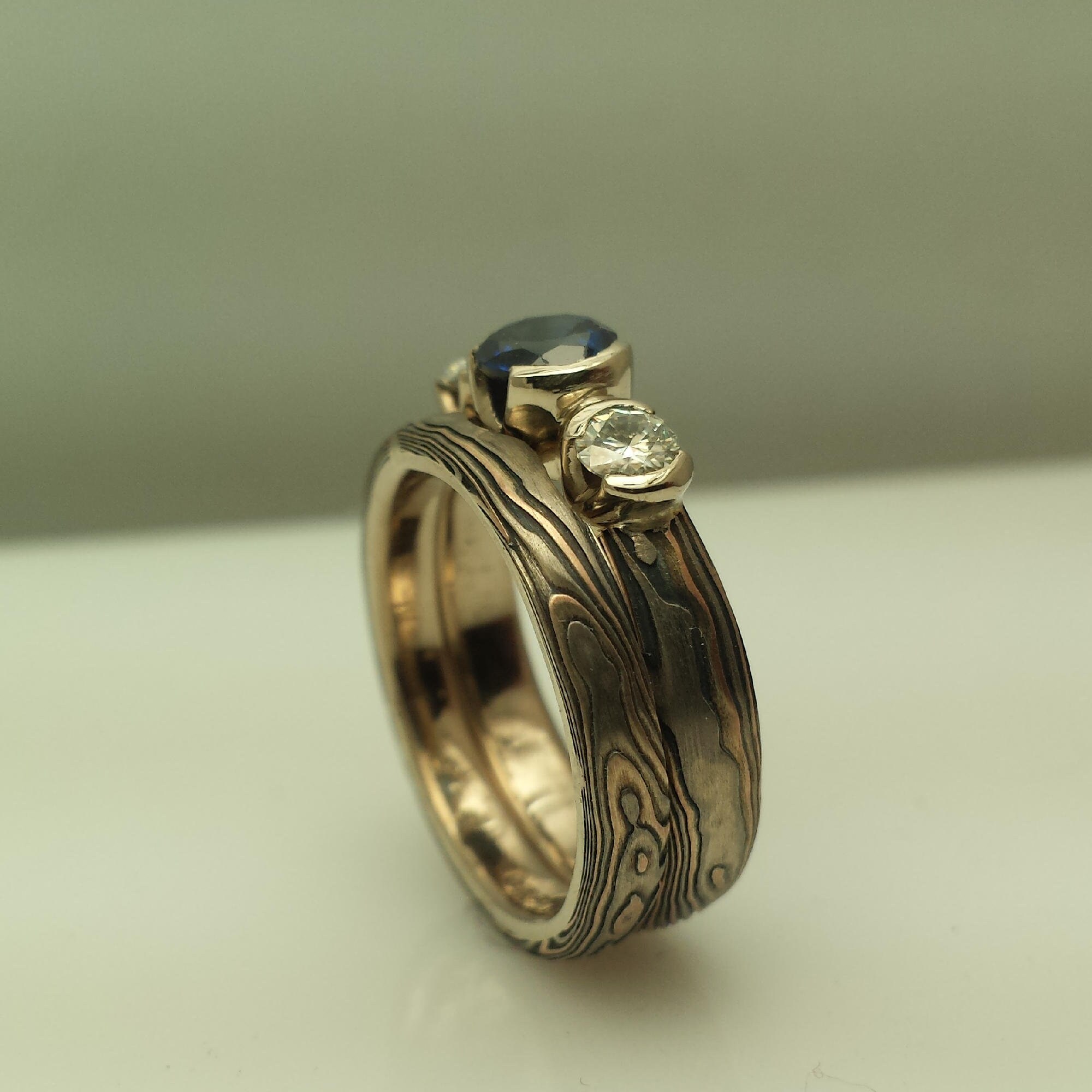 Three stone Mokume Gane wedding rings bridal Set shown with blue sapphire and moissanite