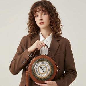 May include: A brown, circular handbag with a clock face design. The bag has a leather exterior with a decorative clock face, Roman numerals, and ornate hands. It has a top handle and a shoulder strap.