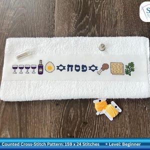 Può includere: Asciugamano bianco a punto croce con simboli pasquali ricamati, tra cui calici, una bottiglia, un uovo e matzah. La parola "פסח" è ricamata in blu. Include due rocchetti di filo giallo. Il motivo è di 159 x 24 punti.