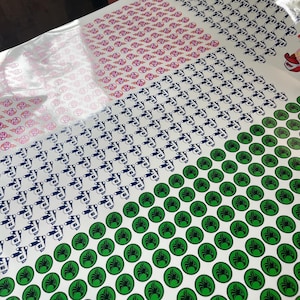 May include: Sheets of stickers with various designs. One section features pink and red circular designs, another has blue and white tattoo machine illustrations, and the last has green circular stickers with a black design. The stickers are on a white background.