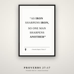 May include: A black framed wall art print featuring the white background text "AS IRON SHARPENS IRON, SO ONE MAN SHARPENS ANOTHER" in a serif font. Below the text is a small black cross symbol and the citation "Proverbs Chapter 27 Verse 17".